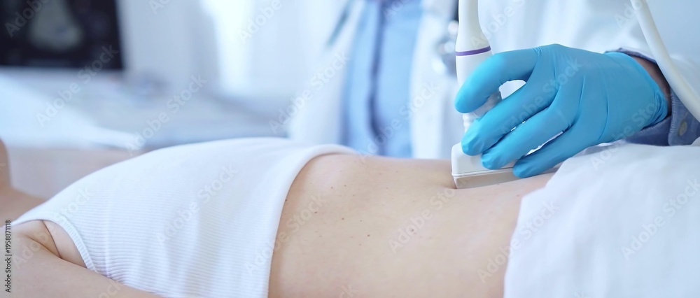 Fototapeta premium Doctor man wearing a blue medical gloves using an ultrasound equipment on a female patient lying down in clinic cabinet, close up view. Medicine concept
