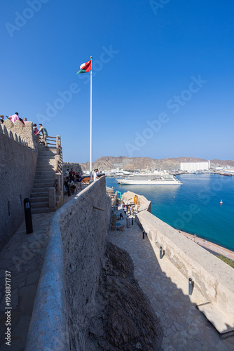 Muscat, Oman – December 28, 2025: View from Mutrah Fort overlooking Muscat harbor with a large cruise ship anchored in the turquoise waters of the Gulf of Oman. The scene captures historic defensive w