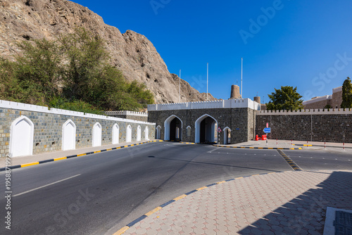 Muscat, Oman – December 28, 2025: Historic stone gate marking the entrance to the old city of Muscat, featuring traditional Omani architecture with arched passageways, crenellated walls and contrastin