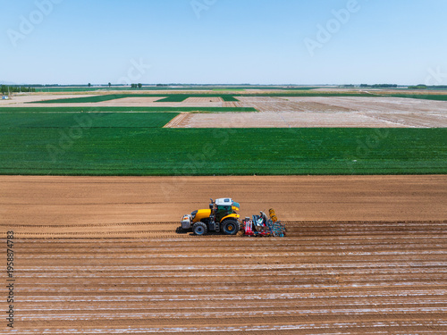 Φωτογραφία In spring, farmers use farm machinery to grow peanuts，Aerial photos of farmers using agricultural machinery to cultivate the land