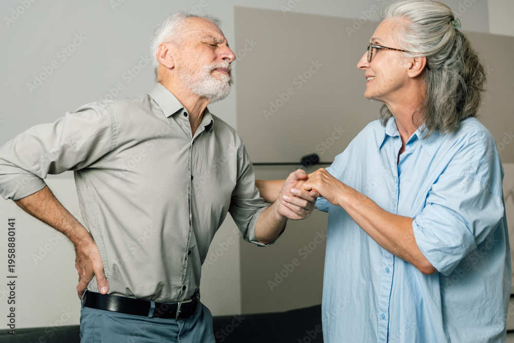 Fototapeta premium Elderly man suffering back pain supported by wife at home