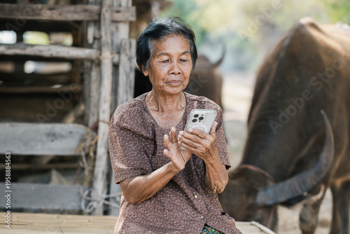 Smiling elderly Asian woman from rural community is happily using her mobile phone. 80 years old grandmother