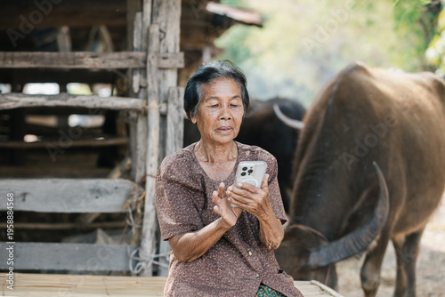 Smiling elderly Asian woman from rural community is happily using her mobile phone. 80 years old grandmother