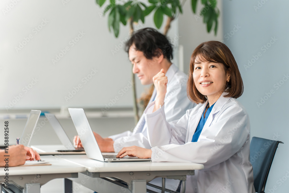 Obraz premium Doctors, both male and female, in white coats, sitting at their desks and working.