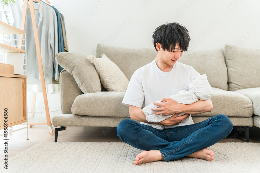 Obraz premium A young Asian man holding a baby in his living room.