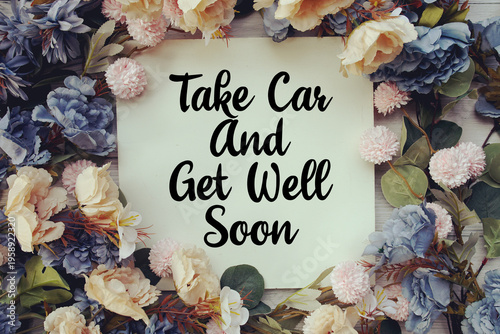 Schilderij op canvas Take Care And Get Well Soon text with flower decoration on wooden background