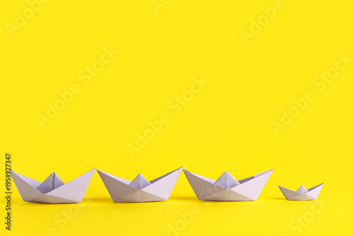Row of origami boats on yel...