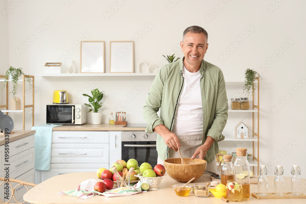 Fototapeta premium Mature man making apple cider at table in kitchen