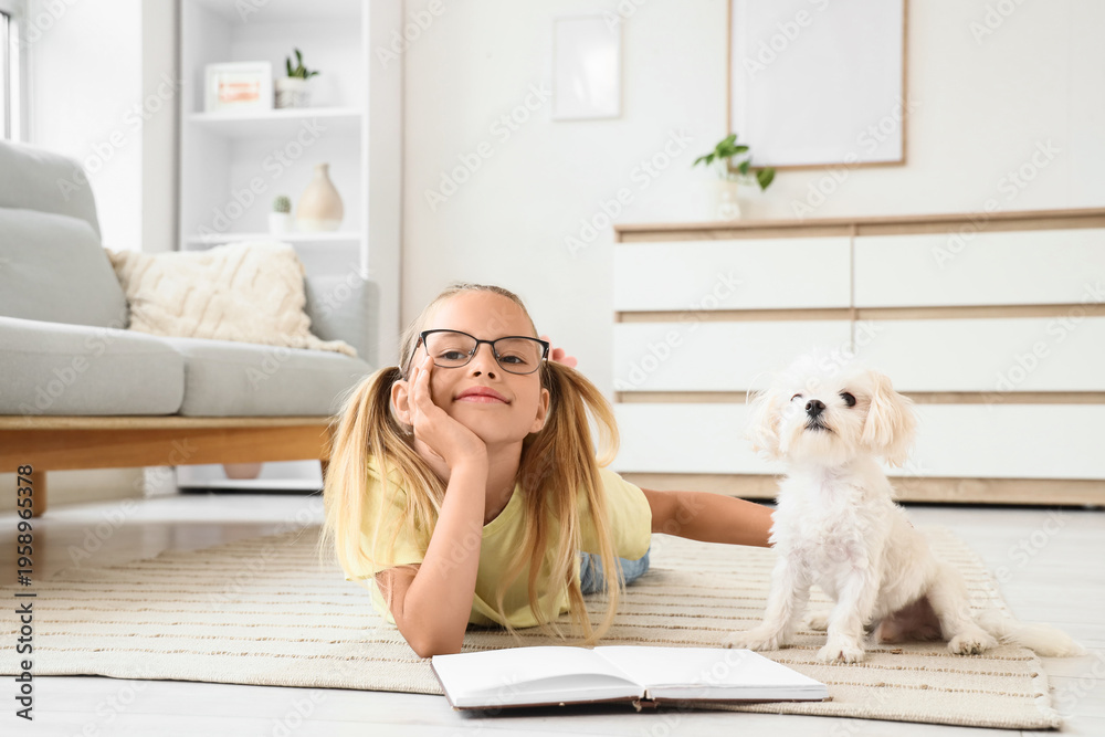 Obraz premium Cute little happy girl with Maltese dog reading book on floor at home