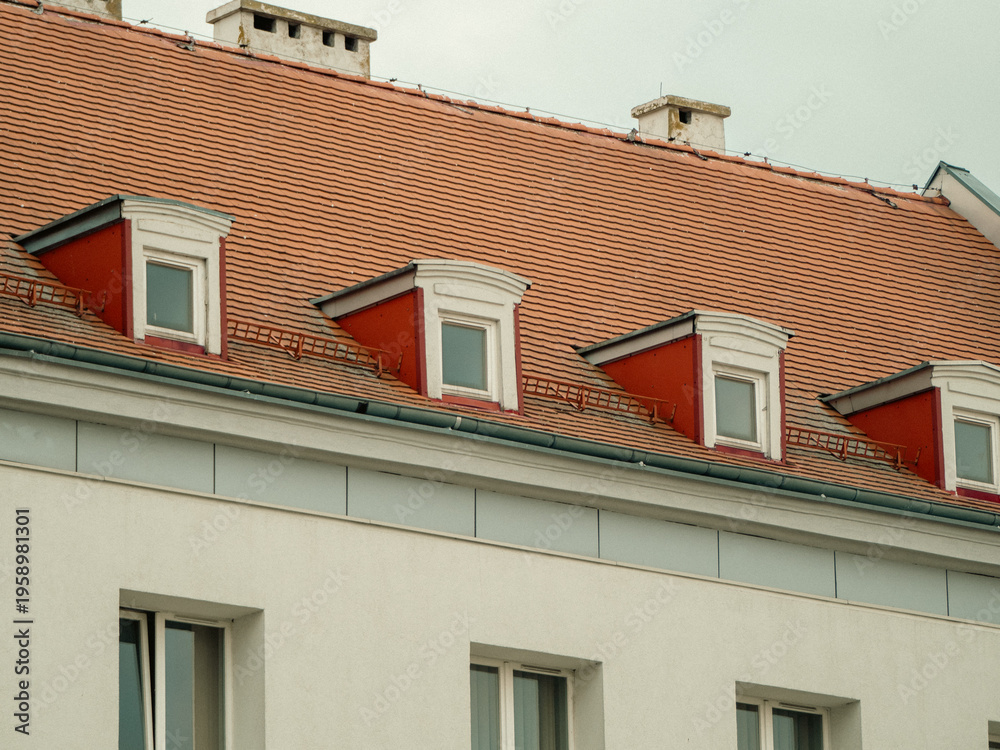 Obraz premium Red-tiled roof with dormer windows above white walls