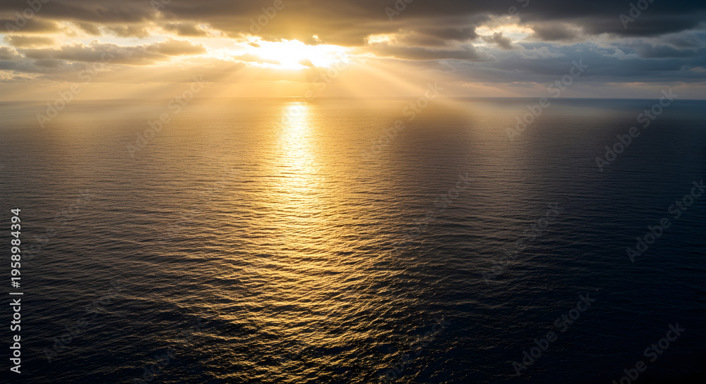 Fototapeta premium Golden Sunset Over the Ocean with Rays of Light Illuminating the Water Surface and Dramatic Clouds in the Evening Sky