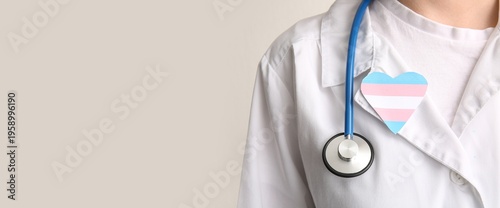 Fotografía Doctor with paper heart in colors of transgender flag on light background with s