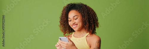 Photos Young brunette isolated on green screen chroma key background with surprise expression while using smartphone, teenage girl surprised, happy and shocked