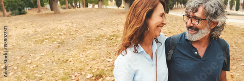 Cuadro en lienzo An older married couple in love walks through the park hugging each other