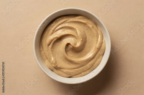 Creamy nut based spread in a minimalist white bowl on soft beige background showcasing smooth texture and inviting tones for culinary creativity