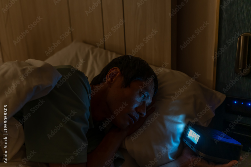 Fototapeta premium man in bed late trying to sleep suffering insomnia, sleepless or scared in a nightmare, looking sad worried and stressed. Tired and headache or migraine waking up in the middle of the night.