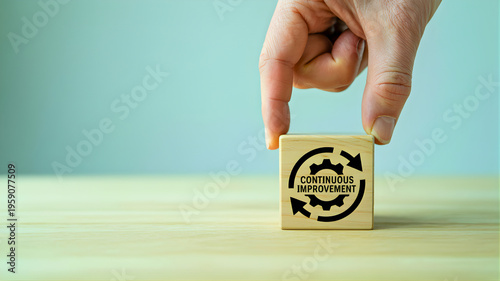 Emphasizing ongoing strategic development and efficient workflow, a hand positions a wooden block featuring the continuous improvement icon, symbolizing business process optimization and growth