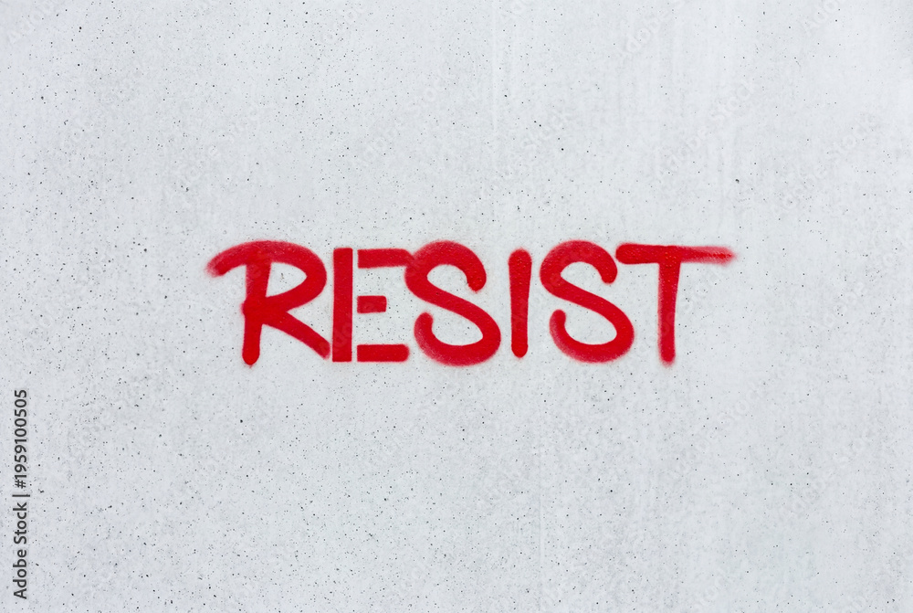Fototapeta premium The word resist painted in bold red spray paint letters on a clean smooth concrete wall