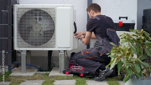Technician servicing outdoor heat pump unit with tools beside residential house. Concept of HVAC maintenance, home climate control and energy efficient heating and cooling