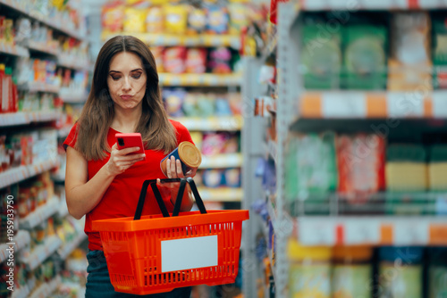 Woman Checking Product Ingredients on the Internet. Woman with shopping basket is confused in a supermarket aisle reading the label