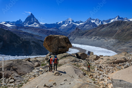 Mountaineers descending towards mountain hut Monte Rosa Hut, glacial erratic and mountain panorama with summits Matterhorn, Dent Blanche, Ober Gabelhorn and Zinalrothorn in Pennine Alps, Switzerland