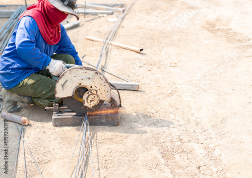 Photography Construction worker using a circular chop saw to cut steel rebar on a sunny worksite
