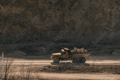 Obraz na plátně A dusty yellow dump truck carrying rocks on a rugged construction site with a ro
