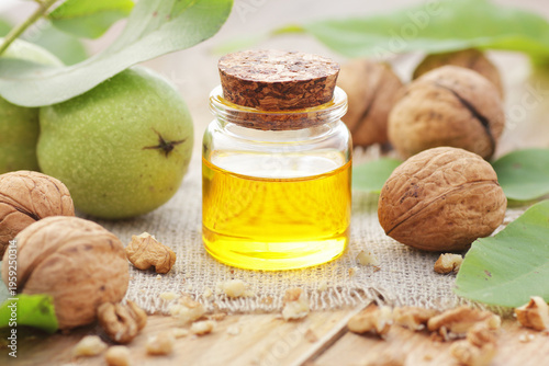 Walnut oil with fresh nut seeds on wooden table, closeup, copy space, cooking ingredient, face skin and hair care, natural organic food concept