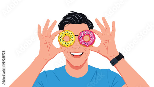 Playful young man having fun while holding two colorful glazed donuts over his eyes like glasses and smiling.