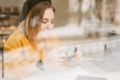Woman with camera and laptop, see through the window