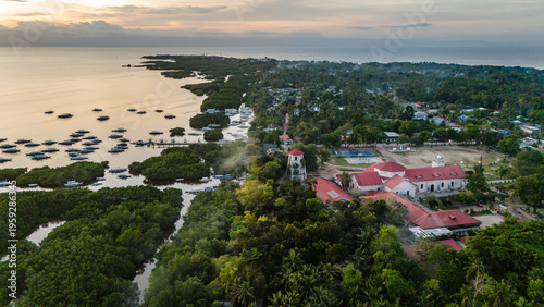 An aerial drone view looking over a traditional coastal village on Panglao Island, Bohol, Philippines. Red-roofed buildings