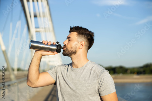 Quadro su tela Young man staying hydrated after a workout, drinking fresh water from a reusable