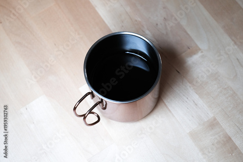Black coffee in a stainless steel cup with light and shadow from window in the morning.