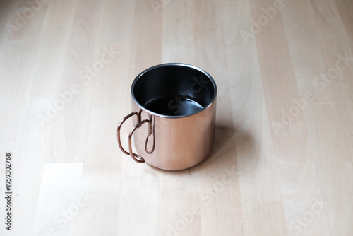 Black coffee in a stainless steel cup with light and shadow from window in the morning.