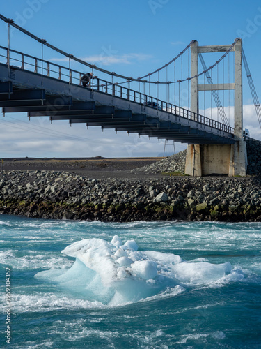 Photographer on the bridge carrying route 1 over Glacier Lagoon in Iceland with icebergs floating underneath