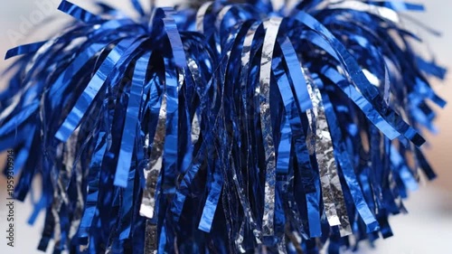 Blue and Silver Pom-Poms Under Indoor Lighting Close-Up – Cheer Accessory Detail