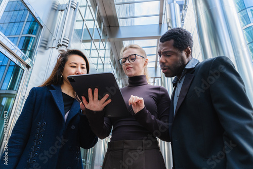 Business colleagues collaborating outdoors with tablet in urban setting