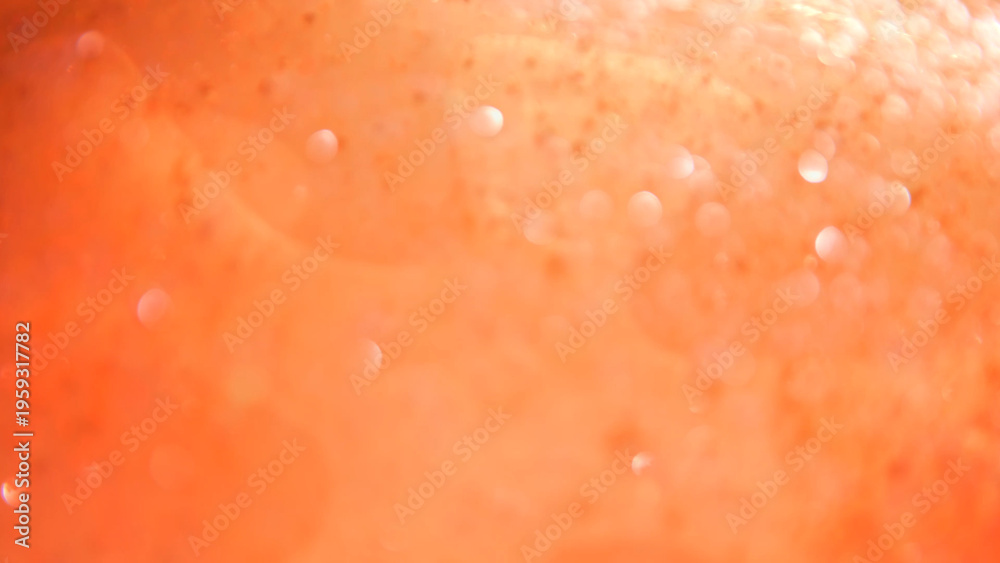 Fototapeta premium Defocused blurred bokeh background of water with paint particle texture in soft orange tones. Concepts for beauty and cosmetology, food and beverage industry, holidays and event designs, advertising.