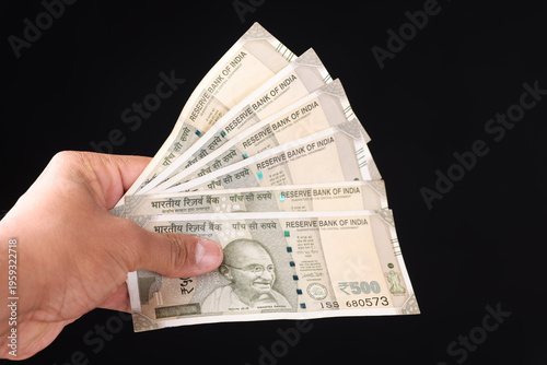 Photos Close-up of hand holding a stack of new Indian 500 rupee currency notes on white background, Wealth and Finance concept