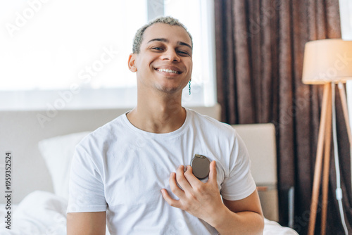 Foto Smiling young man holding modern cardiac pacemaker, showing device for heart rhy