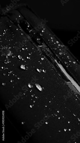 Macro slow motion view of water beads forming on a waterproof surface. Droplets remain intact and do not absorb, showcasing advanced material technology for protection, durability