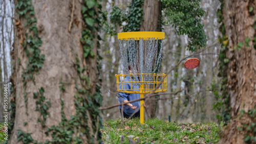 Discgolf basket with player throwing a final shot