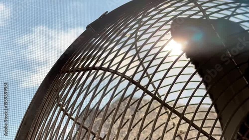 Sun rays passing through an old dirty vintage metal fan against the background of blue sky and mosquito net. Stock video