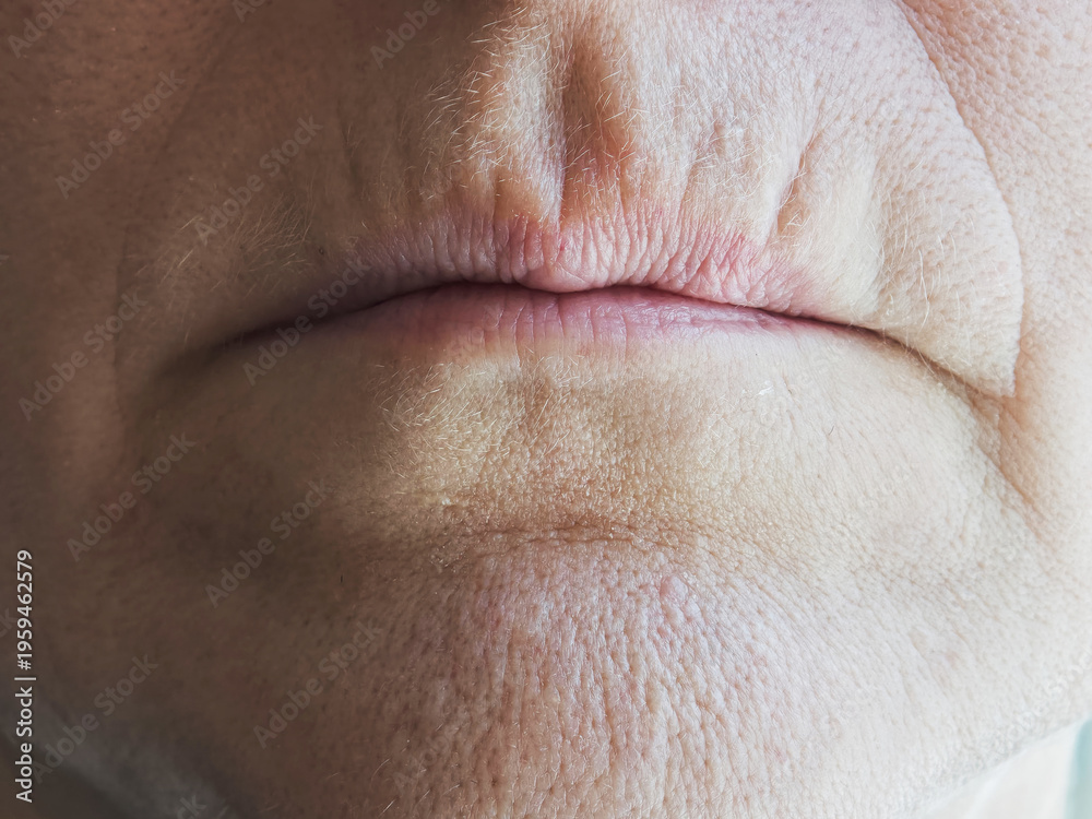 Naklejka premium Mature woman shows details of aging skin with wrinkles and texture on the face in a close-up view