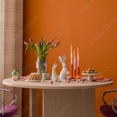 Minimalist Easter brunch setup featuring a modern wooden table, vibrant tulips, and soft pastel decorations against a bold orange wall.