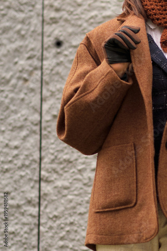 Close-up of a woman s brown wool coat with leather gloves, showing fine texture and stitching. The image conveys autumn elegance, craftsmanship, and minimalist sophistication.