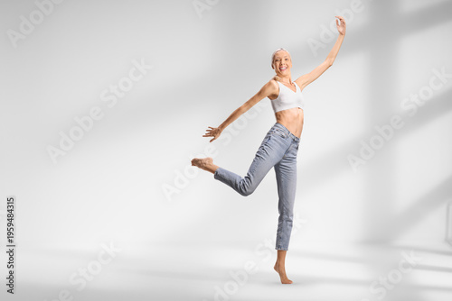 Tall slim woman in jeans and white crop top dancing