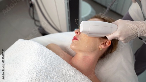 Obraz na płótnie A beautician in gloves performs a non-invasive radiofrequency lifting procedure on a woman's face and neck in a beauty clinic