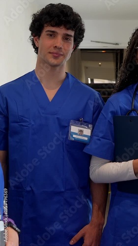 Group of smiling multiethnic medical students wearing blue scrubs and stethoscopes standing in a hospital corridor, representing the next generation of healthcare professionals and teamwork