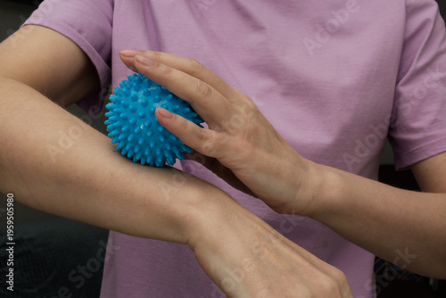 Photos Woman uses blue spiky massage ball on forearm, self massage routine for muscle t